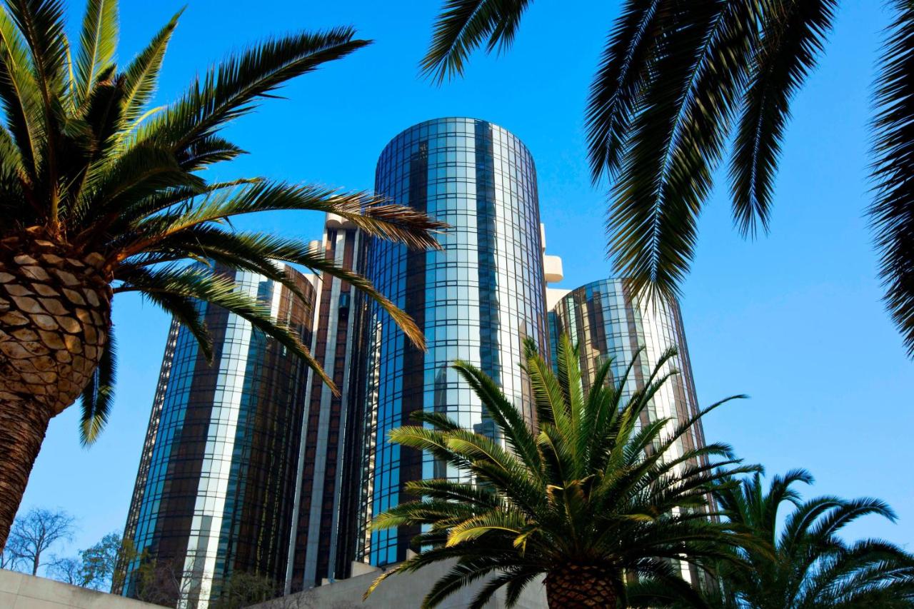 An image of the Westin hotel, a series of round glass buildings, against a blue sky with palm trees in the foreground