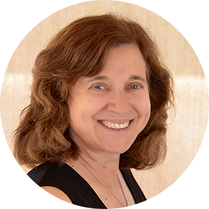 A woman with wavy brown hair cropped at her shoulders smiles at the camera.