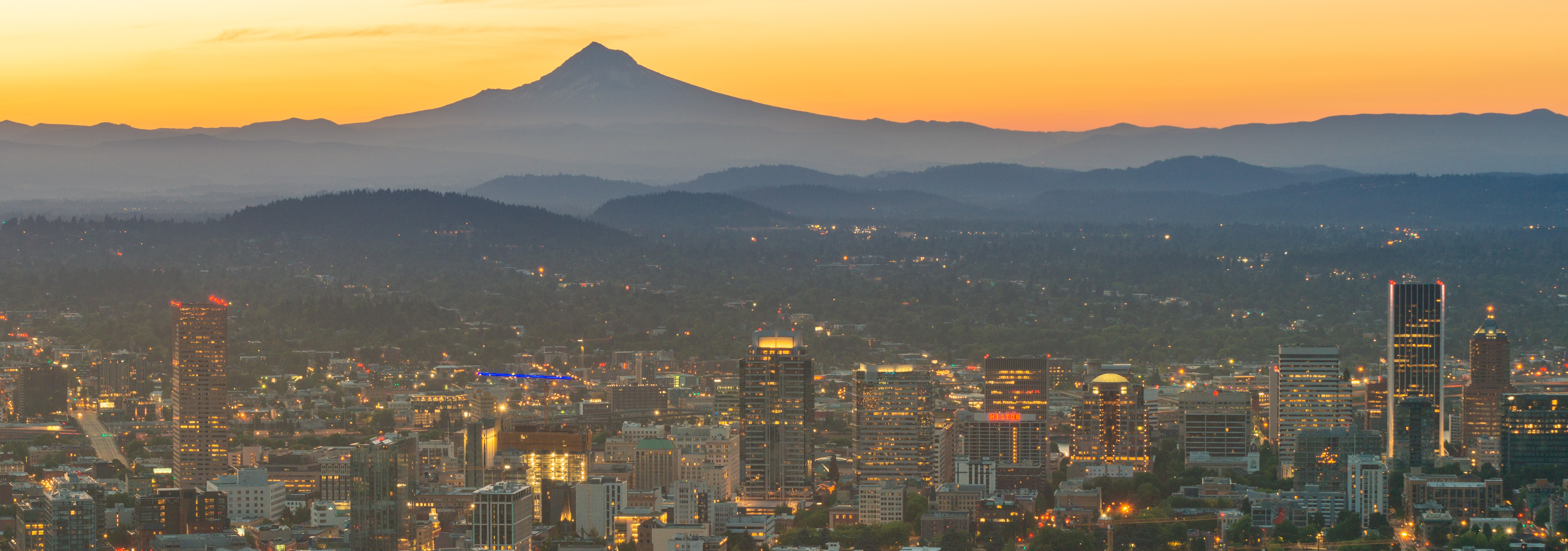 An aerial view of Portland, Oregon, with mountains in the distance.